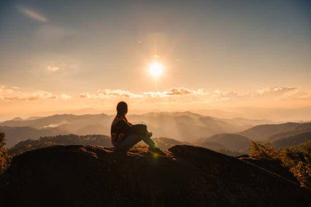 silueta joven mujer excursionista relajándose y disfrutando de la vista del atardecer en la cima del pico de la montaña en el parque nacional - women solitude enjoyment 20s fotografías e imágenes de stock