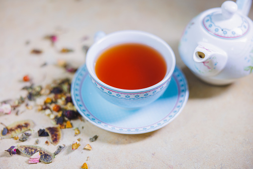 Cup of common mallow tea with fresh blooming malva sylvestris plant on white rustic table, alternative medicine