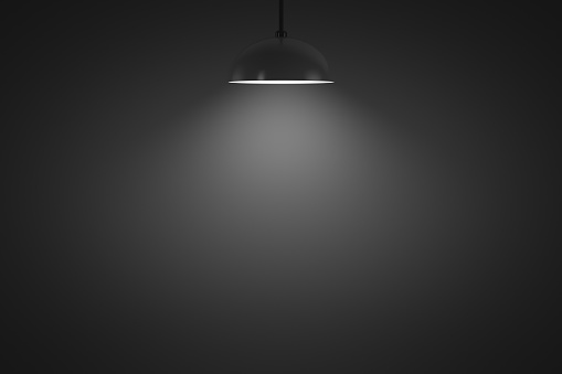 Hanging lamp glows in a dark room. Copy space. Design element.
