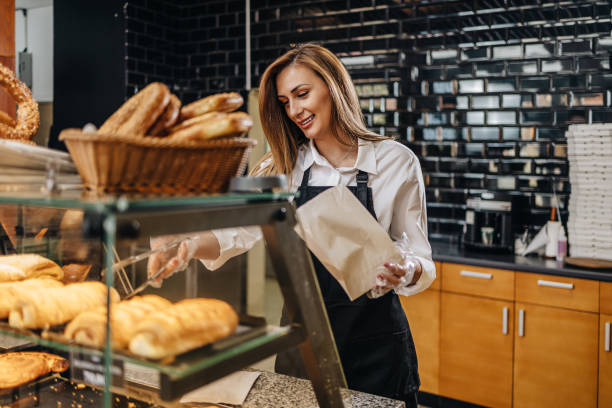 istock Smiling young woman selling bread in the bakery 1392145250