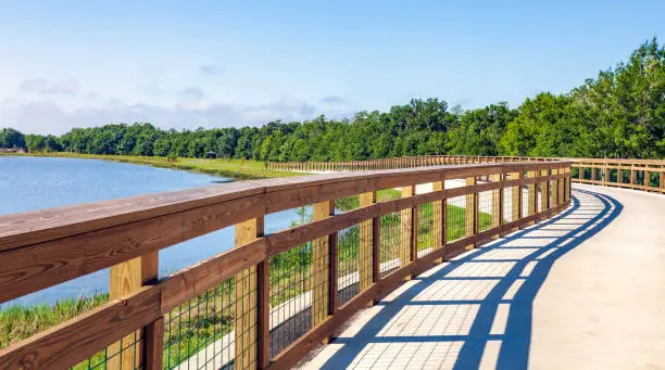 Photo of This concrete foot & bike path with protective wooden railings are part of the Fliorida Trails project. Here it parallels the shore of Shingle Creek within the Shinge Creek Park and Preserve in Kissimmee, Florida