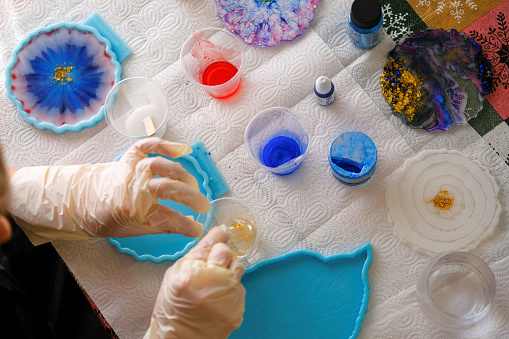 Woman making epoxy resin arts and crafts. Creation of handmade coaster.