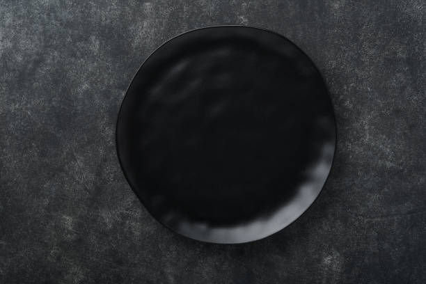 istock Ceramic empty black plate on old black ceramic cement concrete table background. Cooking stone backdrop. Top view with copy space. Flat lay 1392148115