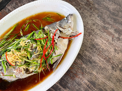 The snapper is cooked by steaming with soy sauce serve on white dish. Thai food Style top view. Fish menu.