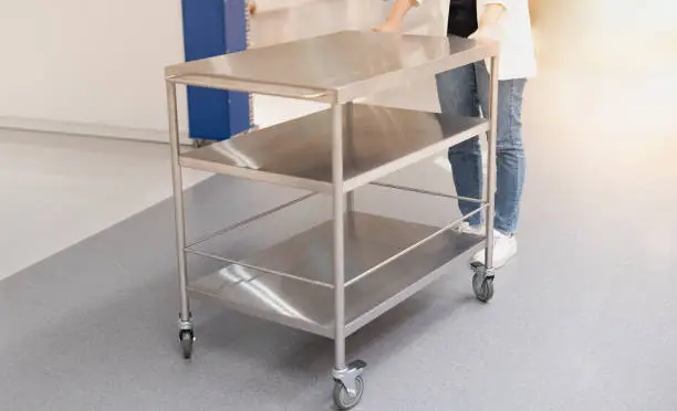 Female hand pushing the stainless steel food trolley cart to the move a lot of parcels.