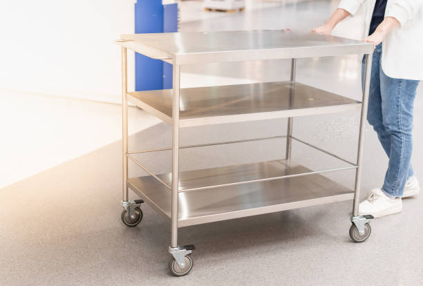 Female hand pushing the stainless steel food trolley cart to move a lot of parcels. stock photo