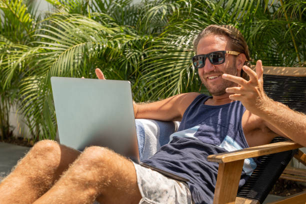istock Young man working online by the pool, he uses a laptop 1392149793