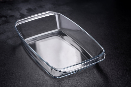 A rectangular glass empty dish for baking on a dark concrete background. Preparation for baking tasty cupcake