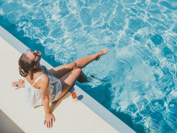mujer de moda sentada junto a la piscina en la cubierta vacía - summer fotografías e imágenes de stock