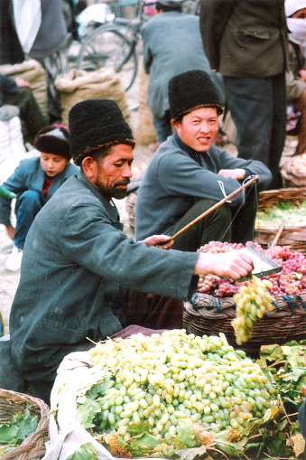 The fruits in Xinjiang is famous and abundant.Fruit farmers in Yutian County sell fruit and use old steelyard.Film was photo on  October 16,1996, in the Yutian County , Xinjiang, China