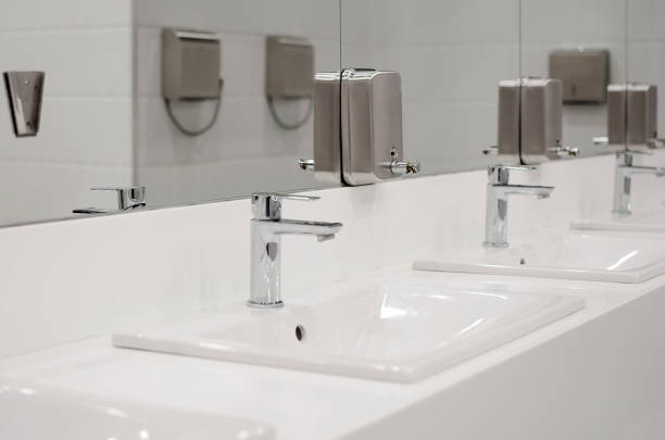istock Modern public toilet interior. Many sinks with faucets for washing hands. 1392165937