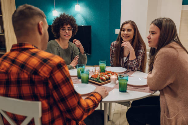 istock Group of friends enjoying dinner while sitting at the kitchen table together 1392166205