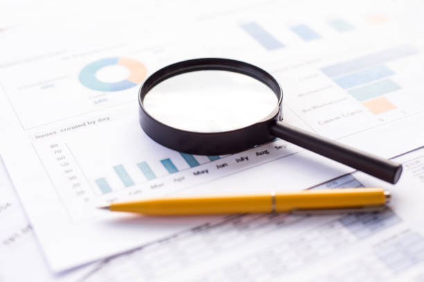 istock Financial chart on papers with magnifying glass and pen. Business accounting documents with graph and report. 1392166227