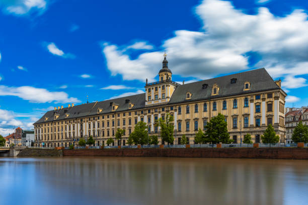 фасад вроцлавского университета в пасмурный день отражается в реке одра - odra river стоковые фото и изображения