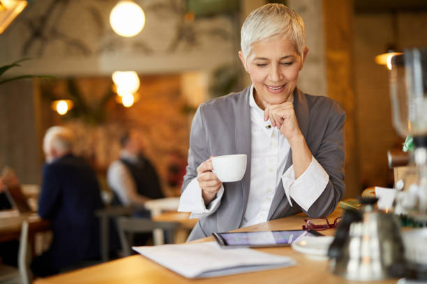 istock Senior businesswoman working on digital tablet in cafe while having coffee break 1392169419