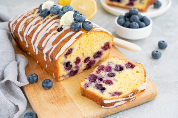 istock Lemon blueberry cake with lemon icing and fresh berries on top on the board on a gray concrete background with cup of tea. Selective focus. Copy space. 1392170345