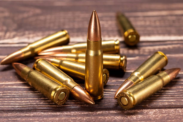 istock Bullets for Kalashnikov assault rifle on wooden background 1392173333