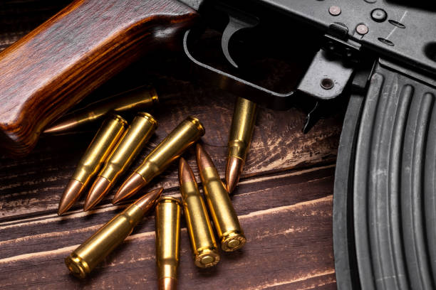 istock Bullets and Kalashnikov assault rifle on wooden background 1392173348