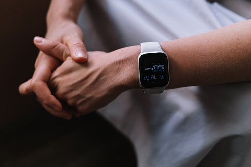 Close up shot of an anonymous woman wearing a smartwatch showing time and weather forecast.