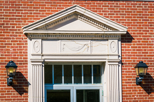 The pointed pediment surrounded by dentil molding and draped fabric design over the entrance of the Town of Sandwich Town Hall Annex.