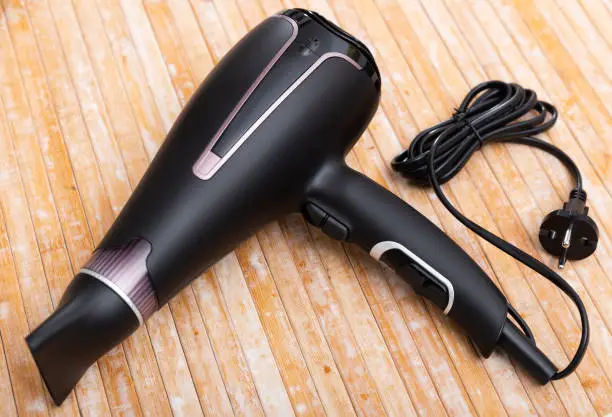 Photo of Black blow dryer on wooden surface