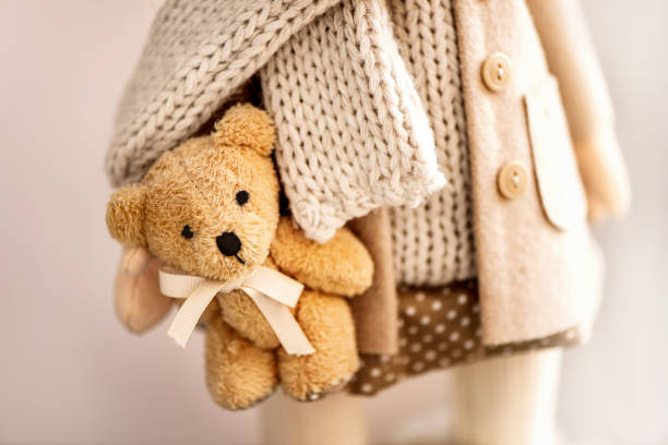 Close up doll holding teddy bear in her hand