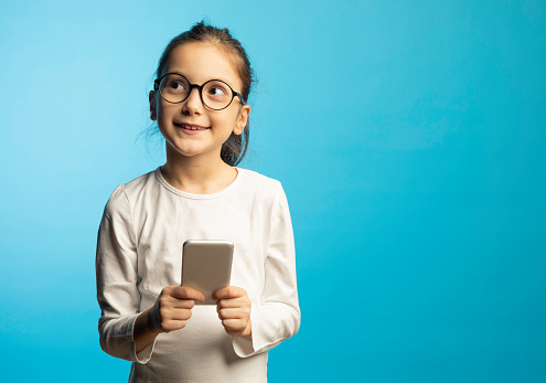 8 years old girl standing against blue background.