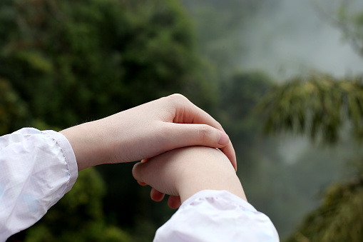 Focus scene on teenage girl's hand against highland cold climate hill background.