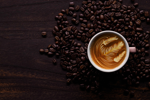 Coffee cup and coffee beans on wooden background. Top view.