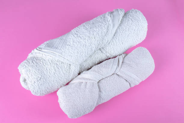 istock Two folded rolled white bathroom towels on pink background. 1392191662