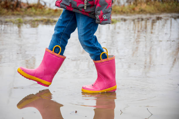 istock Little girl with pink boots walking on a muddy path 1392191964