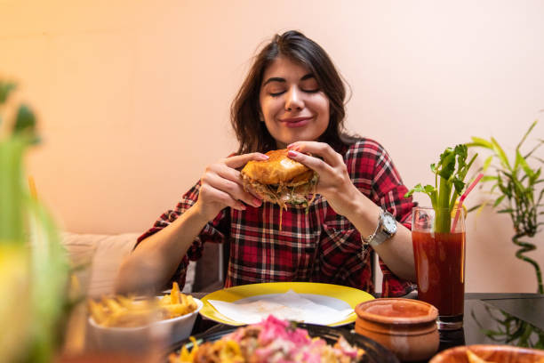 istock Young woman enjoying eating burger and drinking cocktail 1392192128