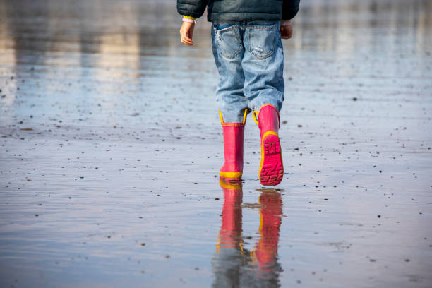 istock Little girl with pink boots walking on a beach 1392192200
