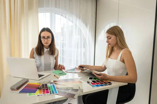 Photo of Two female designers working with house paln and color palette, interior design