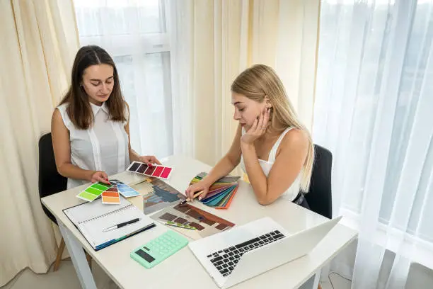 Photo of Two female designers working with house paln and color palette, interior design