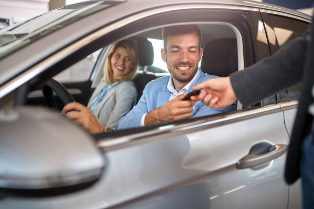 istock Buyer in new car taking key from salesman 1392195545