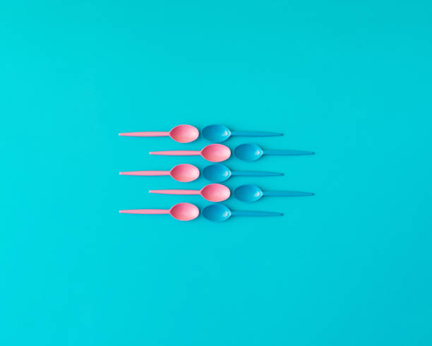 istock Blue and pink plastic spoons on blue background. Fertility art. 1392195707