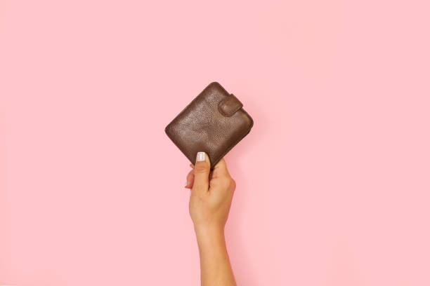 istock Woman hand holding a leather wallet on a pink background 1392197319