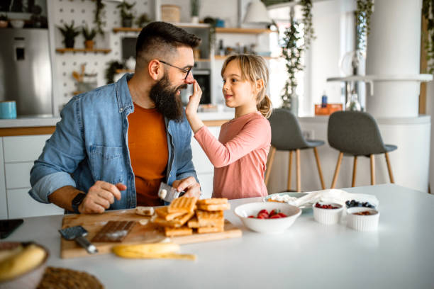istock Cute little girl and her father preparing fruit for decorating waffles 1392201597