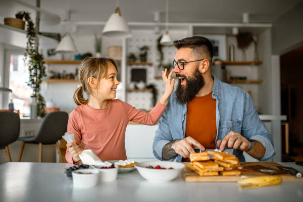 istock Cute little girl and her father preparing fruit for decorating waffles 1392201722