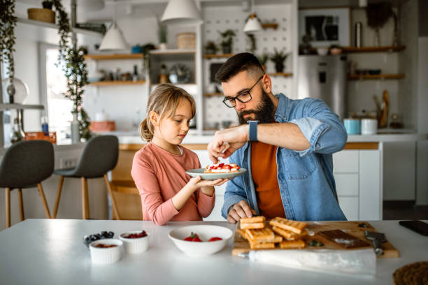 istock Daughter and father decorating waffles with strawberries, blueberries and bananas. 1392201770