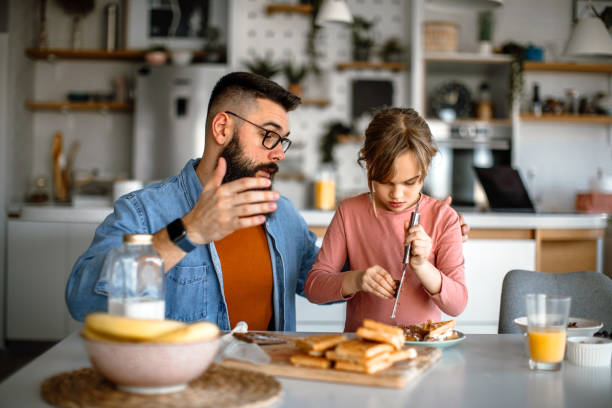 istock Father assisting to her daughter and helping her decorating waffles 1392201865