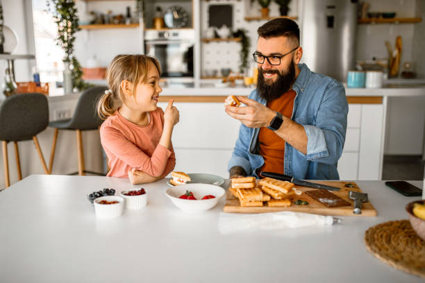 istock Sunday breakfast. Father and daughter having sweet waffles for breakfast. 1392201874