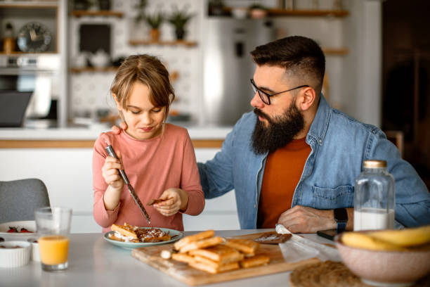istock Father assisting to her daughter and helping her decorating waffles 1392201877