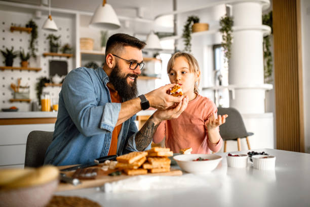 istock Sunday breakfast. Father and daughter having sweet waffles for breakfast. 1392201894