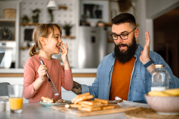 istock Father assisting to her daughter and helping her decorating waffles 1392201936