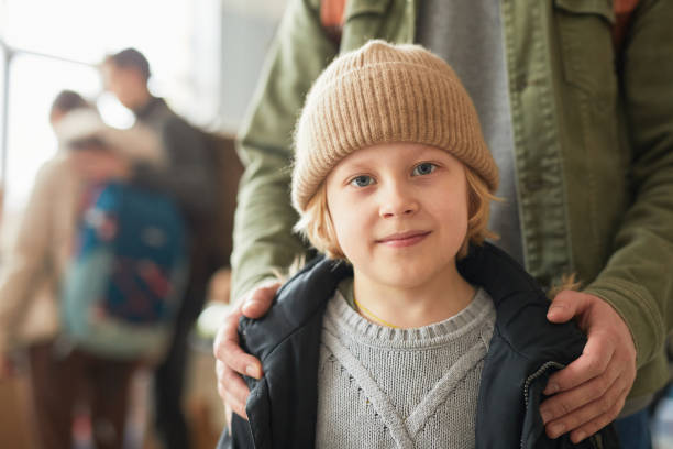 Caucasian Boy in Refugee Shelter Close up of Caucasian young boy with dad looking at camera at help center for refugees, copy space soup kitchen stock pictures, royalty-free photos & images