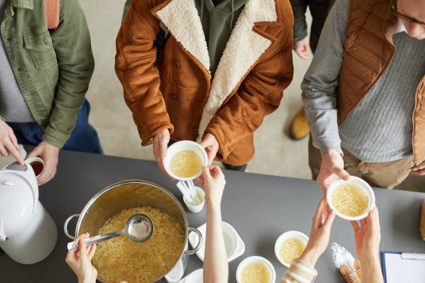 Giving Out Food at Soup Kitchen Top View Top down view at group of volunteers giving out simple meals to people in need at soup kitchen soup kitchen stock pictures, royalty-free photos & images