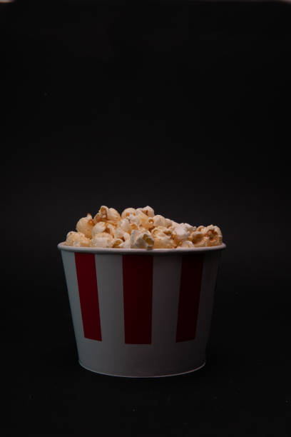 istock a red and white bucket with popcorn on a black background with a creative idea. the concept of a banner for a cinema 1392203300