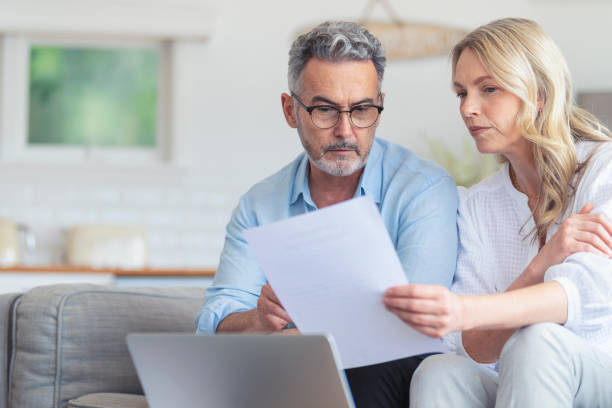 istock Happy mature couple using a laptop computer and doing paperwork on the sofa. 1392204501